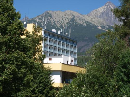 ein Hotelgebäude mit einem Berg im Hintergrund in der Unterkunft Hotel SOREA URÁN in Tatranská Lomnica
