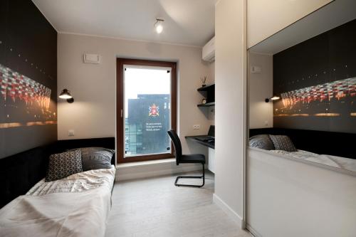a bedroom with a bed and a desk and a window at Bulwary Wislane P&O Serviced Apartments with AC in Warsaw