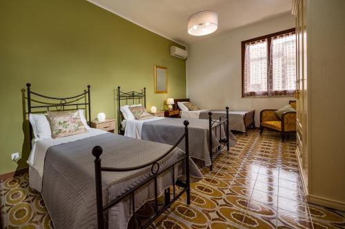 Zimmer mit 3 Betten, einem Stuhl und einem Fenster in der Unterkunft Casa dei Coralli in Castellammare del Golfo