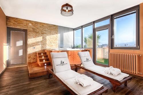una stanza con due sedie bianche e ampie finestre di Penthouse Station Luxury Suites & Apartment a Brindisi