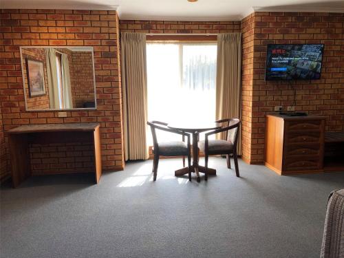 a room with a table and two chairs and a window at Victoriana Motor Inn in Ballarat