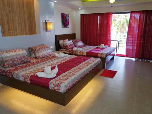 two beds in a room with red curtains at Bellevue Resort in Puerto Galera