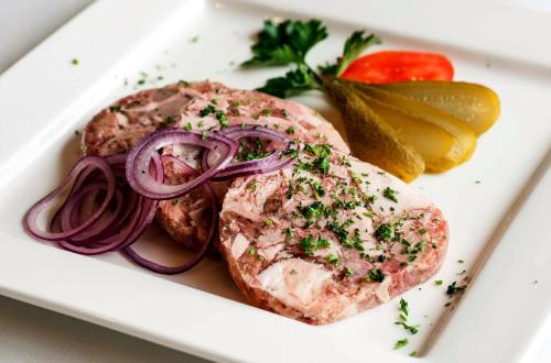 a piece of meat on a plate with onions and pickles at Akzent Hotel Cordes & Restaurant am Rosengarten in Sottorf