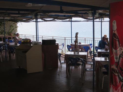 ラッシにあるRegina Apartmentsのテーブルと椅子が備わり、海の景色を望むレストラン