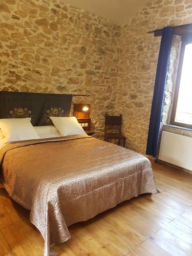 a bedroom with a bed and a stone wall at Domaine de Vareilles in Vareilles
