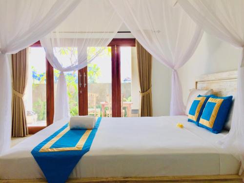 a bedroom with a large white bed with a window at D'uma Amed Homestay in Amed