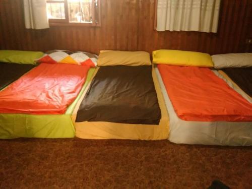 three beds are lined up in a room at Tiger House Guest House in Bcharré