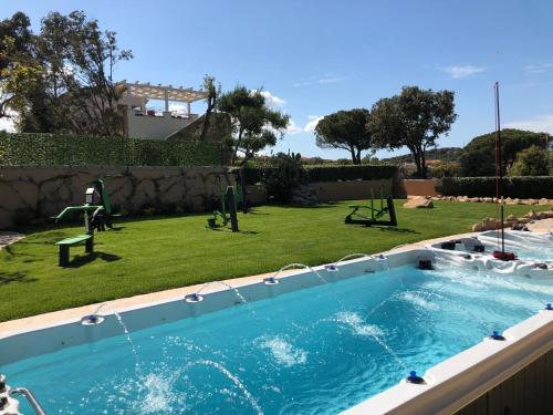 a swimming pool in a yard with a playground at Antica Fonte Holiday Homes in San Pantaleo