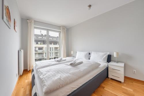 ein großes weißes Bett in einem Zimmer mit Fenster in der Unterkunft Apartamenty Sun & Snow Casa Marina in Świnoujście