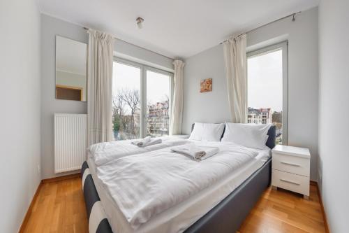 a bedroom with a large white bed with windows at Casa Marina, Sun & Snow in Świnoujście