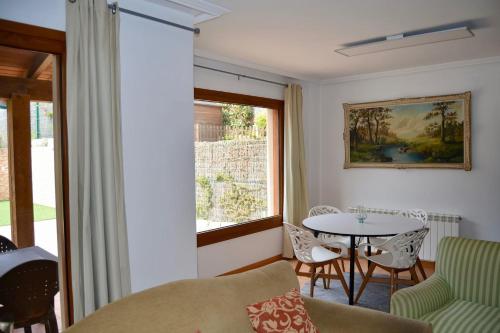 ein Wohnzimmer mit einem Tisch, Stühlen und einem Fenster in der Unterkunft Chalet adosado en Costa Miño a un paso de la playa in Miño