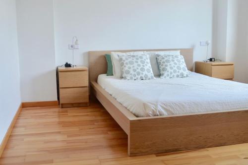 ein Schlafzimmer mit einem Bett und zwei Nachttischen in der Unterkunft Chalet adosado en Costa Miño a un paso de la playa in Miño