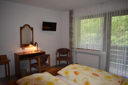 a bedroom with a bed and a desk and a window at Pension Haus am Waldesrand in Schieder-Schwalenberg