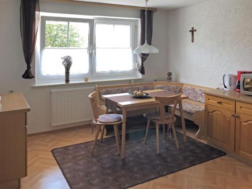 a kitchen with a table and chairs and a cross on the wall at Apartment near the forest in Gößweinstein