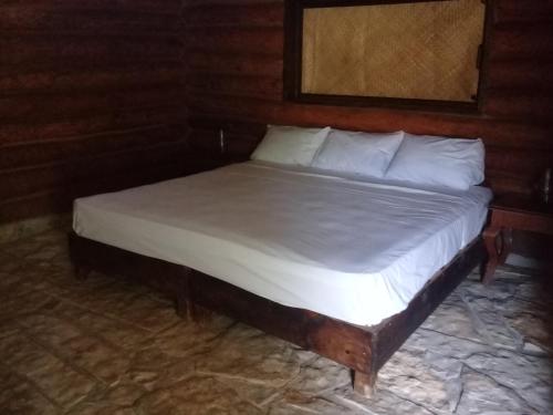 een bed met witte lakens en kussens in een kamer bij Sierraverde Cabins Cabaa la Palma in Tamasopo