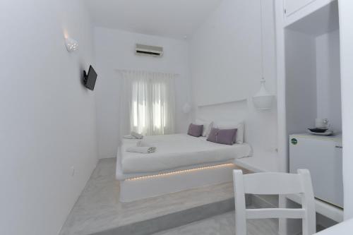 a small white bedroom with a bed and a chair at Eleftheria Veloudiou in Tinos Town
