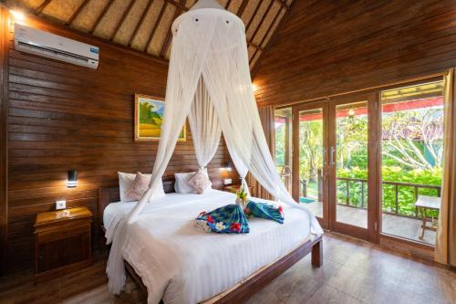 a bedroom with a bed with a mosquito net at Taos House Nusa Lembongan by Best Deals Asia Hospitality in Nusa Lembongan