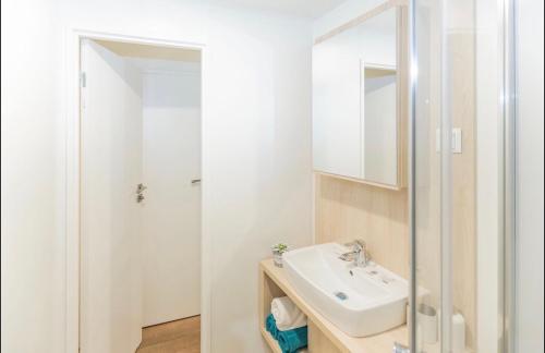 a white bathroom with a sink and a mirror at Mobilheim Murnersee Haus 5 in Wackersdorf