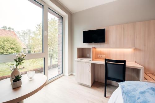 Schlafzimmer mit einem Schreibtisch und einem Tisch mit einem Stuhl in der Unterkunft Gasthaus Großenmeer in Ovelgönne