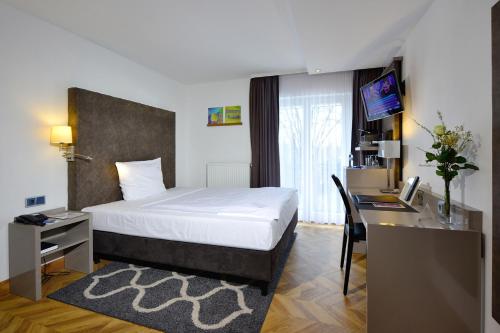 a bedroom with a bed and a desk with a computer at Hotel Caroline Mathilde in Celle