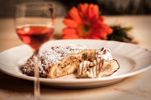 a piece of cake on a plate next to a glass of wine at Herol - my mountain retreat in Luson