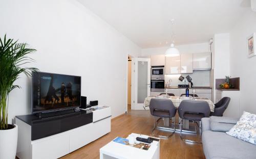 sala de estar con TV y mesa con sillas en Sea view Tiho Apartment en Split