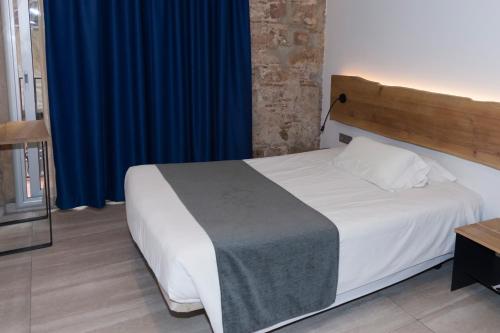 a bedroom with a white bed with a blue curtain at Hostal Paris in Barcelona