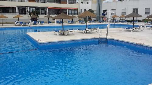 a swimming pool with chairs and umbrellas in a building at Apartamento La Nogalera in Torremolinos