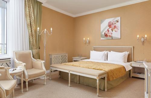 ニジニ・ノヴゴロドにあるGrand Hotel Oka Premiumのベッド1台と椅子2脚が備わるホテルルームです。