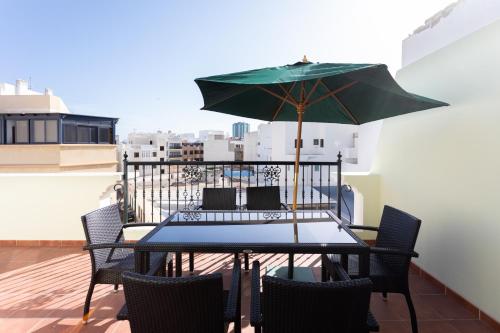 a table and chairs with an umbrella on a balcony at Rooms & Suites Terrace 3A in Arrecife