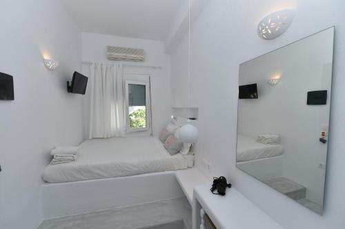 een witte kamer met 2 bedden en een spiegel bij Eleftheria Veloudiou in Tinos Town