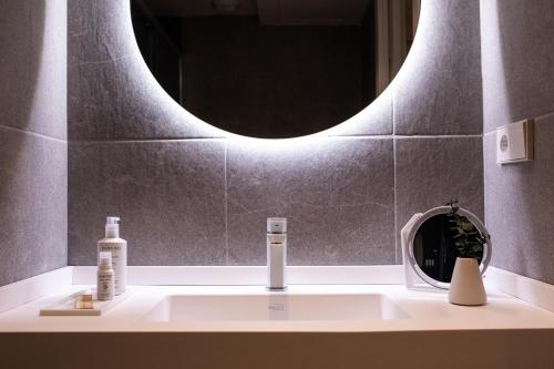 a bathroom sink with a round mirror above it at Room Mate Cosmo - City Centre, Valencia in Valencia