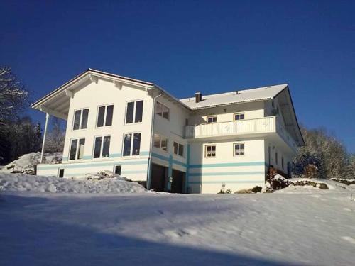 a white house with blue stripes in the snow at Ferienwohnung Brunner in Grafenau