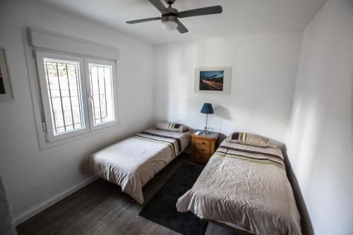 ミハス・コスタにあるVilla del Solのシーリングファン付きの客室内のベッド2台