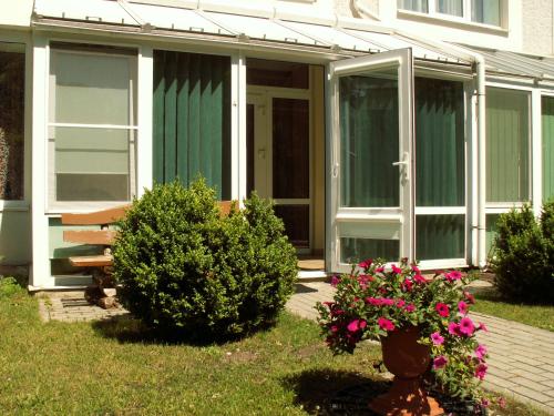a green house with a bench and some flowers at Prie Ąžuolo in Juodkrantė