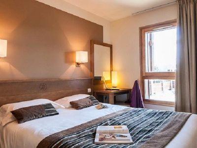 ein Hotelzimmer mit einem Bett mit einem Buch darauf in der Unterkunft Flaine prime ski in, ski out Apartment in Flaine