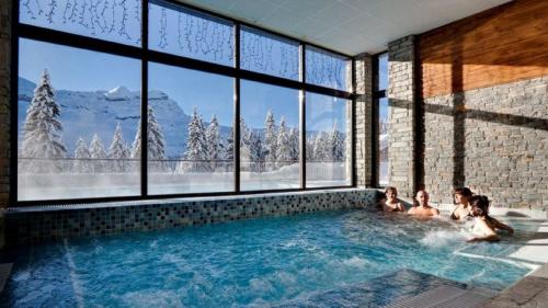 un grupo de personas en una piscina con ventanas en Flaine prime ski in, ski out Apartment, en Flaine