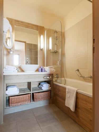 une salle de bain avec un lavabo, une baignoire et un miroir dans l'établissement Flaine prime ski in, ski out Apartment, à Flaine