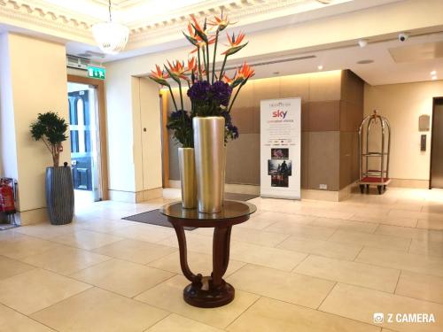 a vase with flowers in it sitting on a table at The Park City Grand Plaza Kensington Hotel in London