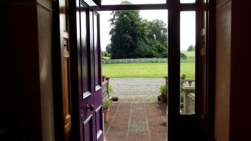 eine offene Tür eines Hauses mit Blick auf einen Hof in der Unterkunft Gardenvale Manor House B&B in Stranocum