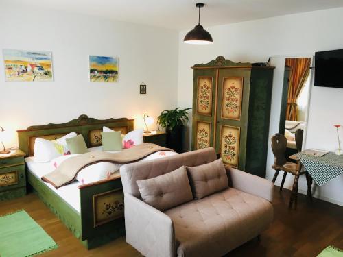 ein Schlafzimmer mit einem Bett, einem Sofa und einem Stuhl in der Unterkunft Pension Marillenhof in Melk