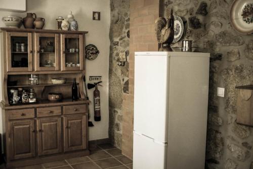 a kitchen with a refrigerator and a wooden cabinet at The Bakery Guesthouse in Fundão