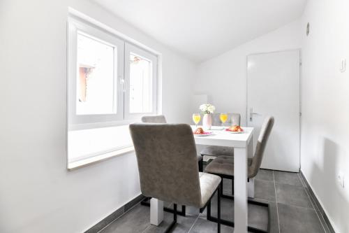 a white dining room with a white table and chairs at GREY Apartment Old Town in Zadar
