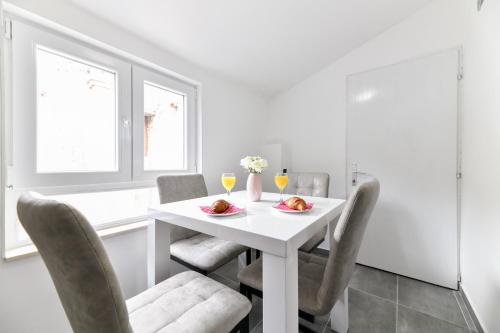 a white dining room with a white table and chairs at GREY Apartment Old Town in Zadar