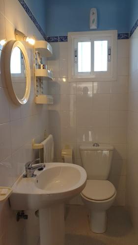 a white bathroom with a toilet and a sink at La Hoya in Agua Amarga