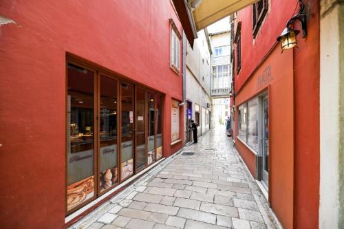 an alley with red buildings and a person walking down a street at GREY Apartment Old Town in Zadar