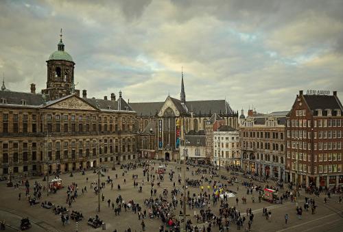 eine Menschenmenge, die durch eine Stadt mit einem Uhrturm geht in der Unterkunft Hotel TwentySeven - Small Luxury Hotels of the World in Amsterdam