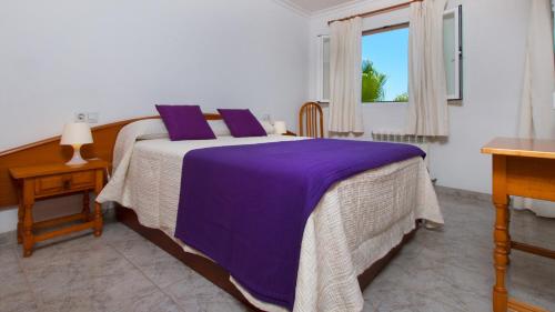 a bedroom with a bed with purple sheets and a window at Villa Estrella del Mar Azul Alcudia in Alcudia