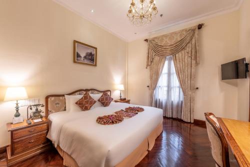 a bedroom with a large white bed and a window at Hotel Grand Saigon in Ho Chi Minh City