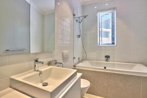 a white bathroom with a sink and a bath tub at Warwick Mansions 7 in Cape Town